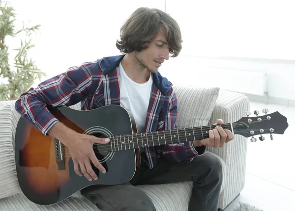 Yakışıklı adam evde kanepede gitar çalmaya