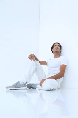 Beyaz bir duvar oturan rüya gibi genç adam.