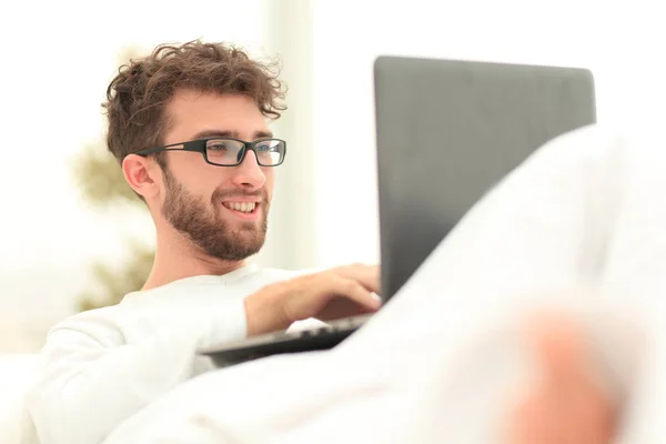 微笑的人使用膝上型电脑躺在床上 — 图库照片