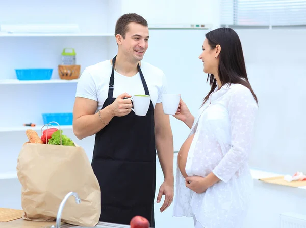 Муж и его беременная жена с чашкой какао, стоящей на кухне . — стоковое фото