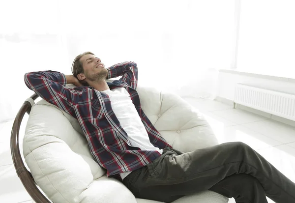 Moderne man rust in een grote comfortabele stoel zitten. Zijaanzicht. — Stockfoto
