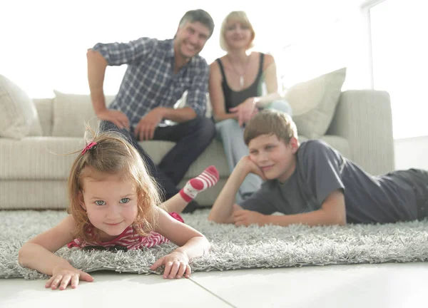 Retrato de crianças enquanto os pais sentados no sofá na sala de estar — Fotografia de Stock