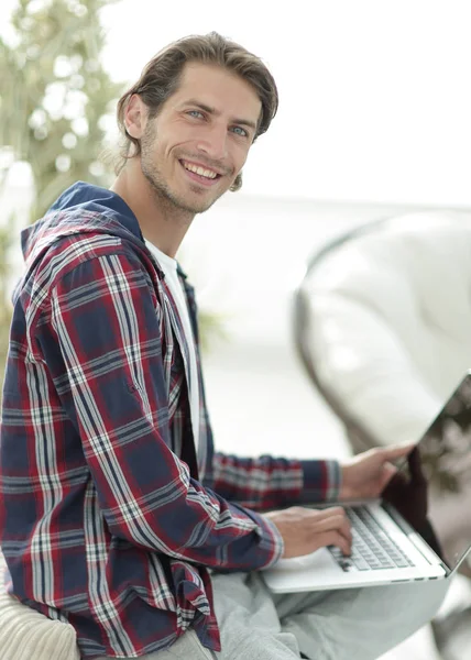 dizüstü bilgisayarda çalışan ve kameraya bakarak şık genç adam