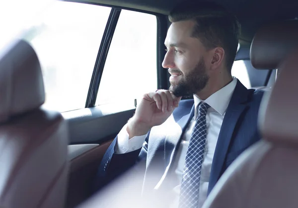 Uśmiechający się biznes człowiek siedzący na tylnym siedzeniu samochodu — Zdjęcie stockowe