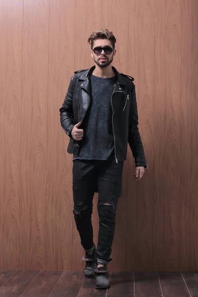 Un hombre está de pie en una chaqueta de cuero negro y jeans —  Fotos de Stock