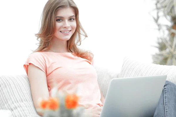 Menina bonita com um laptop sentado no sofá . — Fotografia de Stock