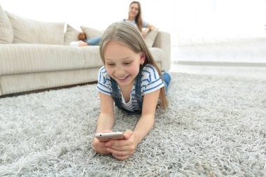 Anne ve kızı geniş oturma odasında kendi smartphones kullanarak