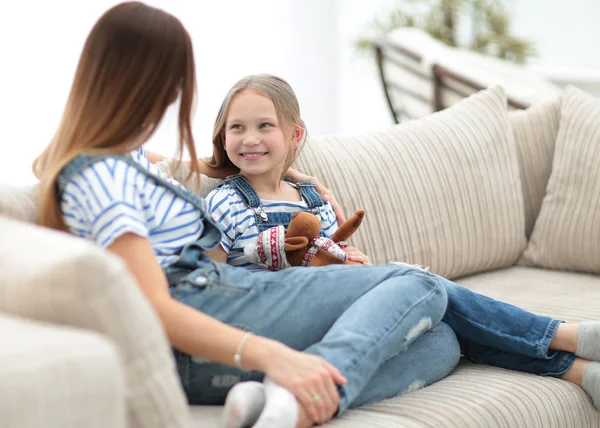 Mãe e filha sentados no sofá em uma sala de estar aconchegante — Fotografia de Stock