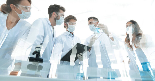 учёные, работающие с пробирками и микроскопом в лаборатории
