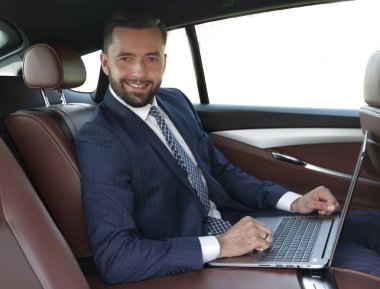 Arabanın içinde otururken dizüstü klavye üzerinde işadamı