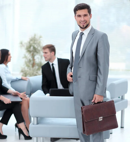 Selbstbewusster Geschäftsmann mit Aktentasche steht in der Lobby des Büros. — Stockfoto