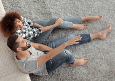 yeni bir oturma odasında bir halı üzerinde oturan yeni evli çift