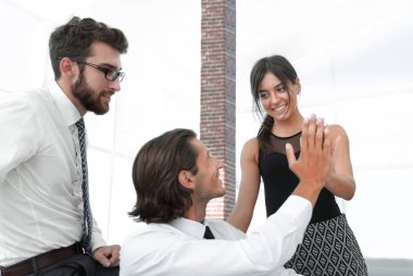 Birbirimizi bir beşlik veren genç iş arkadaşları