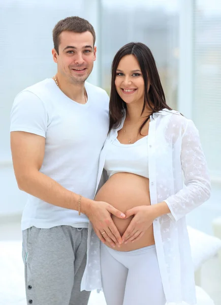 Mann und schwangere Frau mit gefalteten Händen in Herzform auf dem Bauch — Stockfoto