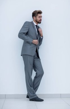 İş takım elbiseli yakışıklı bir genç adam portresi. duvarın yanında ayakta