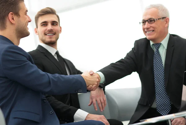 Socios concluyendo trato y estrechando la mano en presencia de los miembros del equipo — Foto de Stock