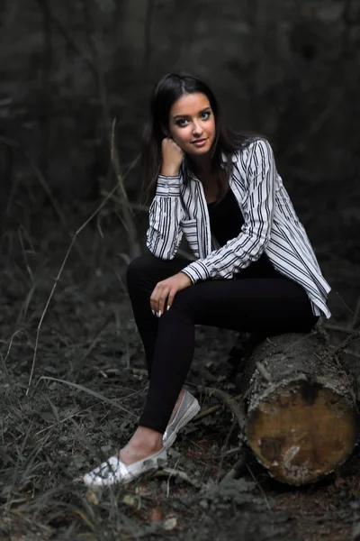 Mujer joven sentada en un tronco en el bosque . —  Fotos de Stock