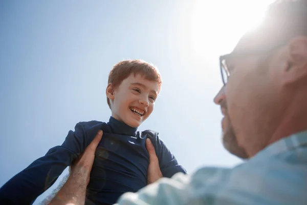 Gestileerde photo.a gelukkige zoon in zijn vaders veilige handen — Stockfoto