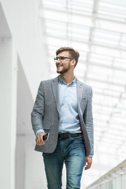 Kendine güvenen bir iş adamı parlak bir ofiste yürür.