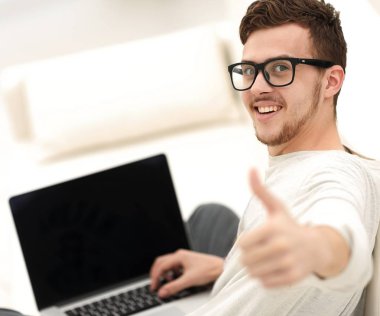 açık belgili tanımlık laptop önünde oturan ve gösterilen modern genç yukarı başparmak