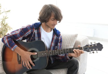 Yakışıklı adam evde kanepede gitar çalmaya