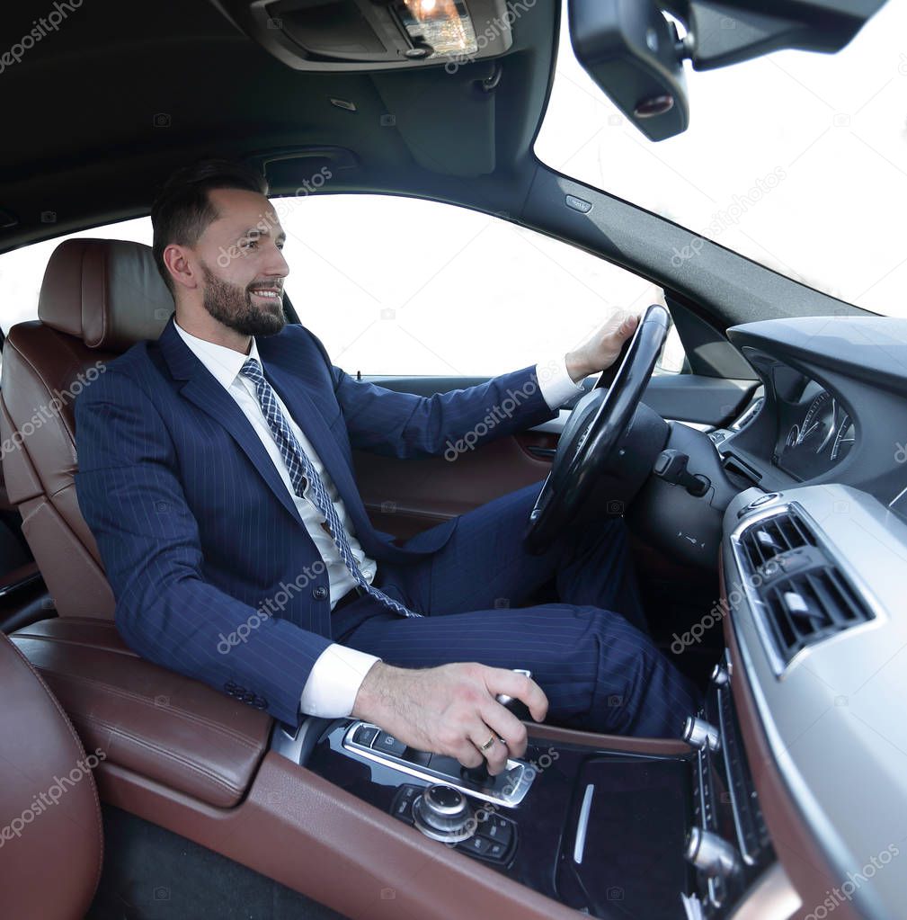 View from the side confident businessman sits at the wheel of a car