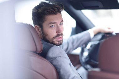 Başarılı bir adam prestijli bir arabanın direksiyonunda oturuyor.