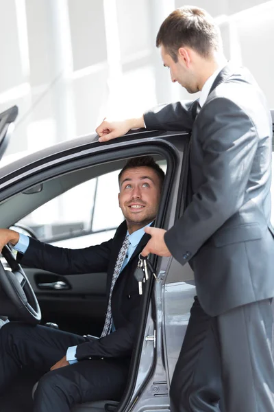 Homme d'affaires prospère, recevant les clés de la voiture du vendeur dans la salle d'exposition — Photo