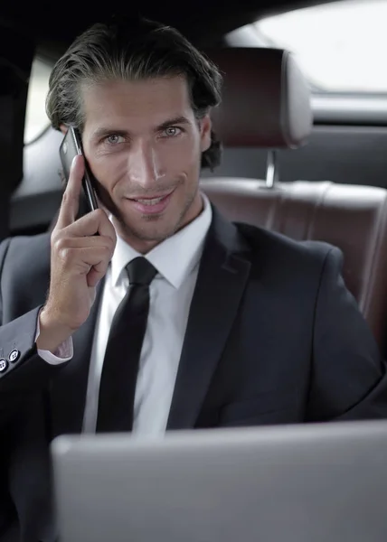 Beau homme d'affaires utilisant le téléphone portable dans la voiture . — Photo
