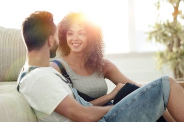 Yeni evliler yeni bir dairede kanepede oturuyor..