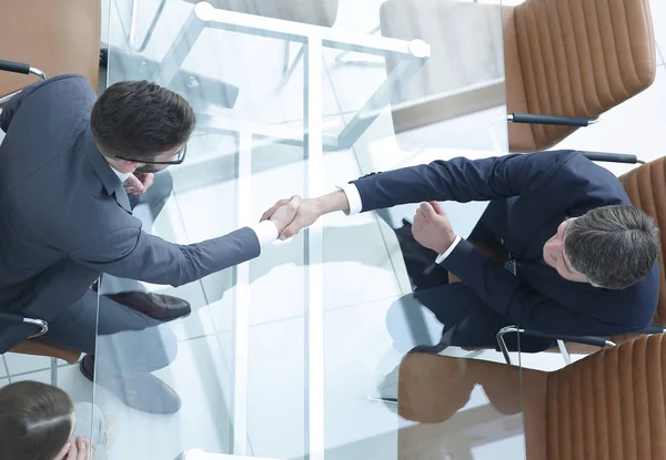 Um aperto de mão na mesa. Reunião em torno de uma mesa de reuniões. — Fotografia de Stock