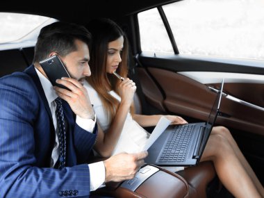 Genç iş adamları arabada birlikte çalışıyorlar.