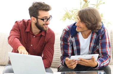 dizüstü ve tablet kanepede oturan çalışan iki genç adam
