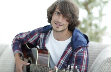 modern adam kanepede oturan gitar çalmak. bir yaşam tarzı kavramı