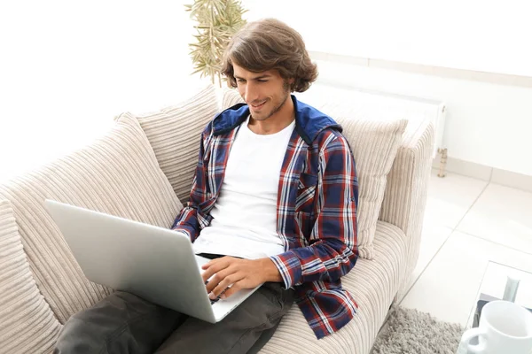 Giovane uomo che lavora su laptop seduto sul divano — Foto Stock