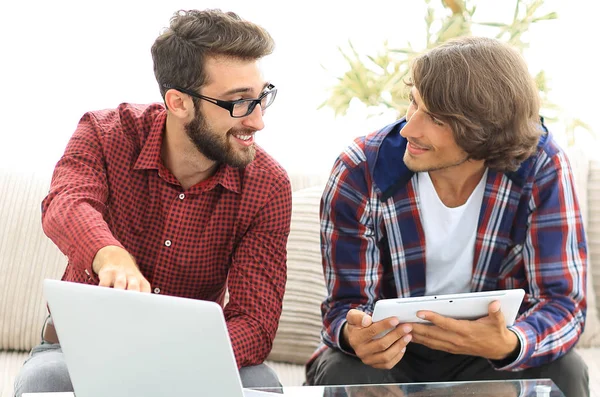 dizüstü ve tablet kanepede oturan çalışan iki genç adam