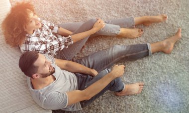 yeni bir oturma odasında bir halı üzerinde oturan yeni evli çift