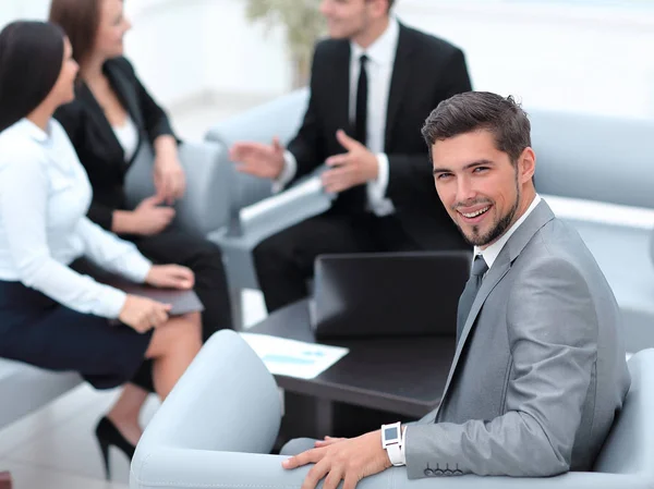 Zakenman zit in een kantoor op de achtergrond van business team. — Stockfoto