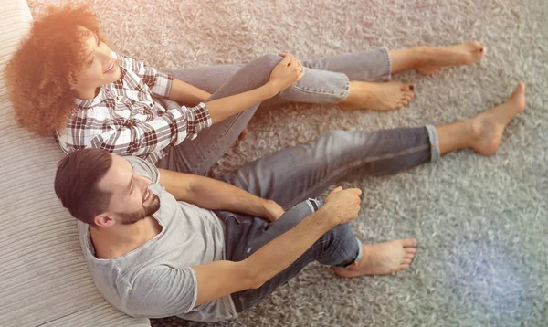 Newlywed couple sitting on a carpet in a new living room — Stock Photo, Image