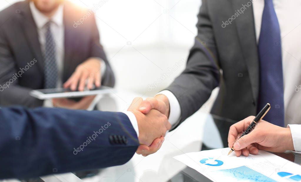 Men shaking hands with smile at office with their coworkers.