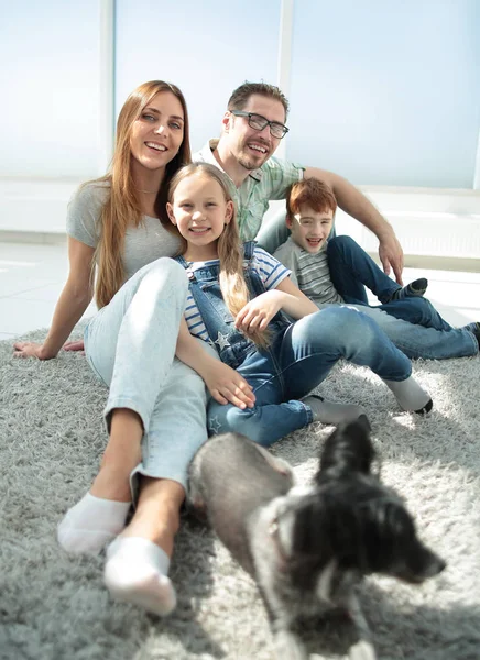 Retrato de una familia feliz sentada en el piso del salón — Foto de Stock