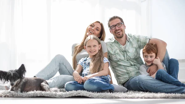 neşeli aile yeni oturma odasında halı üzerinde oturan