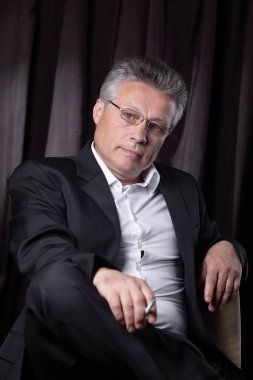 bir sandalyede oturan bir sigara ile üst düzey iş adamı