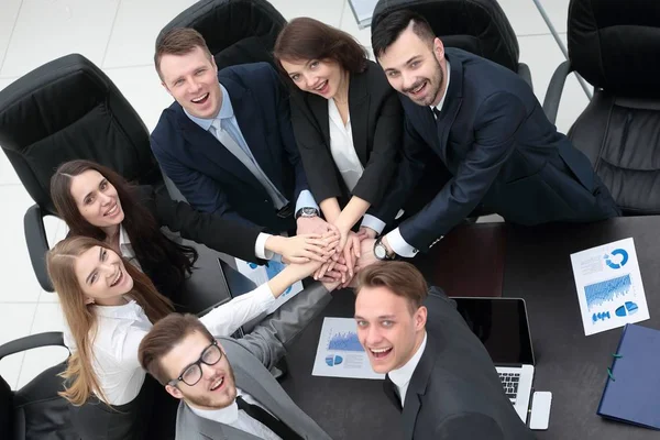 Equipo de negocios con las manos juntas en el escritorio — Foto de Stock