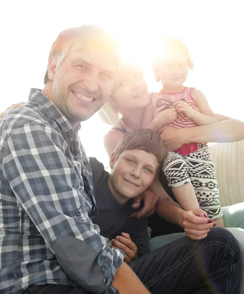 Gezin met twee kinderen elkaar zitten en kijken naar camera — Stockfoto