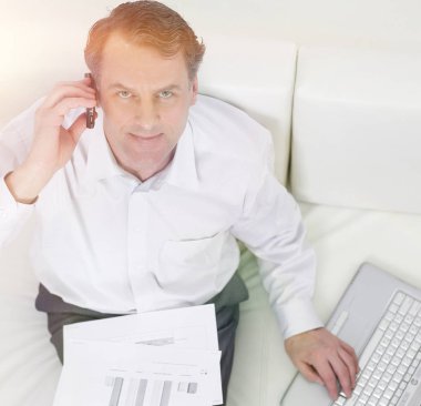 sandalyede oturan ve bir smartphon üzerinde konuşurken işadamı