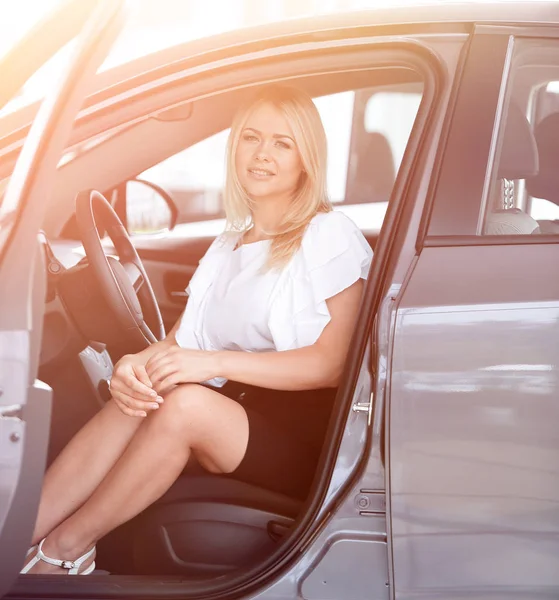 Successful young woman sitting in the cabin of a new car. — Stock Photo, Image