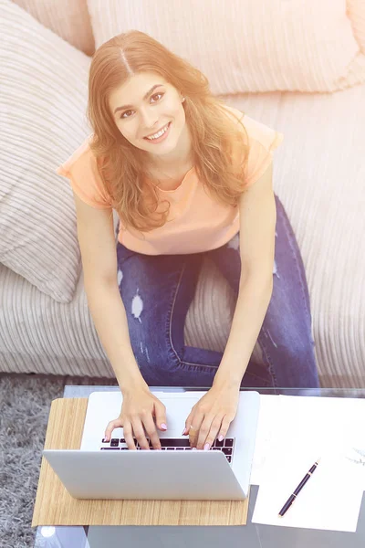 Студентка работает на ноутбуке, сидя возле кофейного столика — стоковое фото
