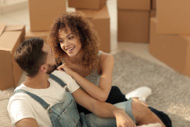 Genç bir çift yeni bir dairede yerde oturuyor.