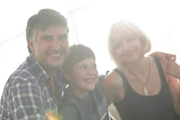 Ouders en hun zoon zitten opeengepakte in de woonkamer en lachende — Stockfoto